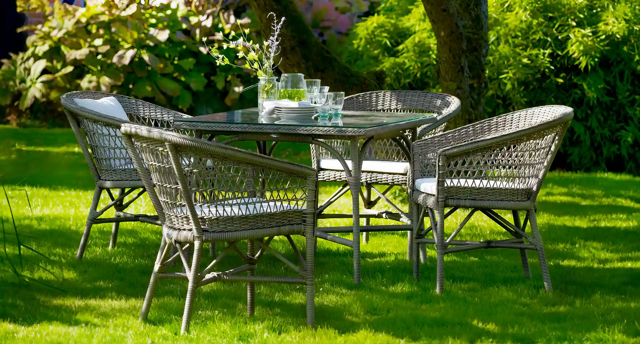 A serene grassy setting features a wicker table and chairs, representing the garden furniture Bell Plantations in Towcester, UK.