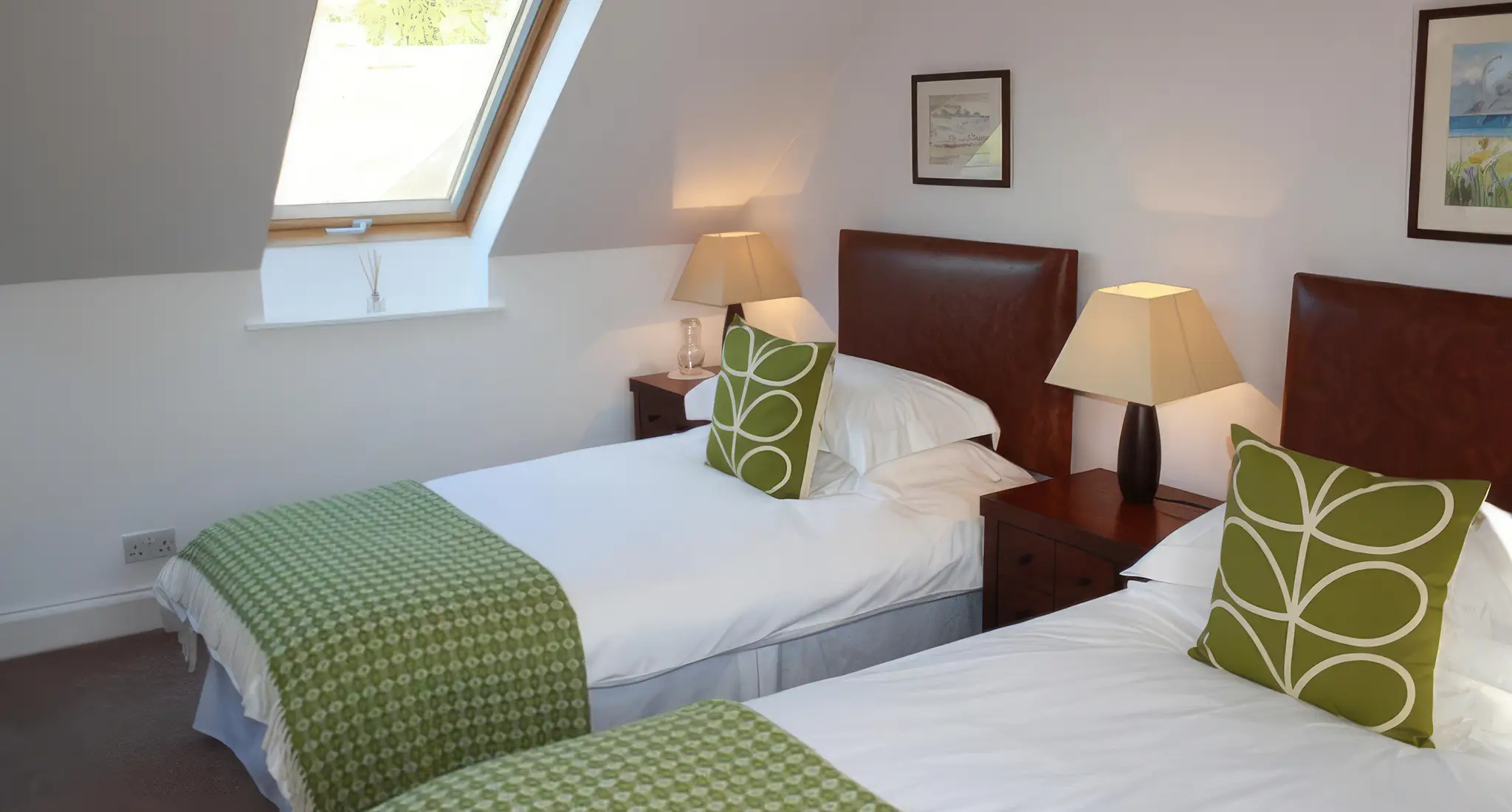 Two neatly made beds with crisp white linens in a cozy room adorned with a window, located at Baldiesburn Hotel in Scotland.